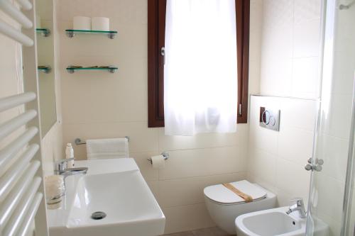 a white bathroom with a toilet and a sink at PIUMABLU in Campi Bisenzio