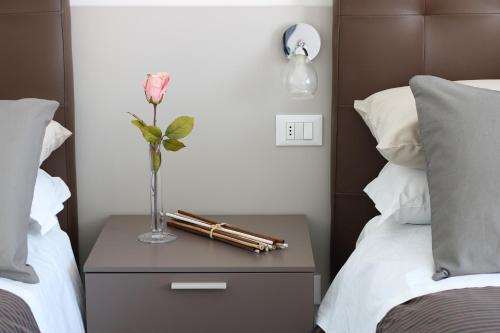 wazon z kwiatem na stoliku nocnym pomiędzy dwoma łóżkami w obiekcie PIUMABLU w mieście Campi Bisenzio