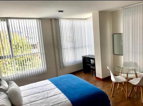 1 dormitorio con 1 cama, mesa y sillas en Floresta Inn Hotel, en Ambato