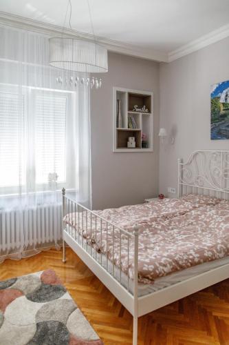 a white bedroom with a bed and a window at Central Luxury apartment in Novi Sad