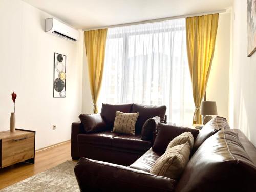 a living room with a brown leather couch and a window at Pirin Dream View Apartments in Razlog