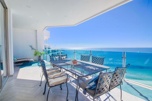 una mesa de cristal y sillas en un balcón con vistas al océano en Esmeralda Beach Resort en Puerto Peñasco