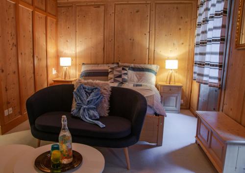 a living room with a chair and a bed at Hotel Corona in Vicosoprano