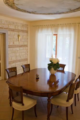 a dining room table with chairs and a vase of flowers on it at VILLA EVA in Sirolo