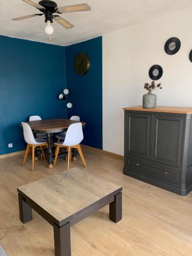 una sala da pranzo con tavolo e parete blu di L'appart Fréjus plage a Fréjus