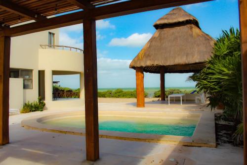a villa with a swimming pool and a thatch roof at Villa Karpatos in Progreso