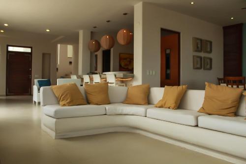 a living room with a white couch with yellow pillows at Villa Karpatos in Progreso