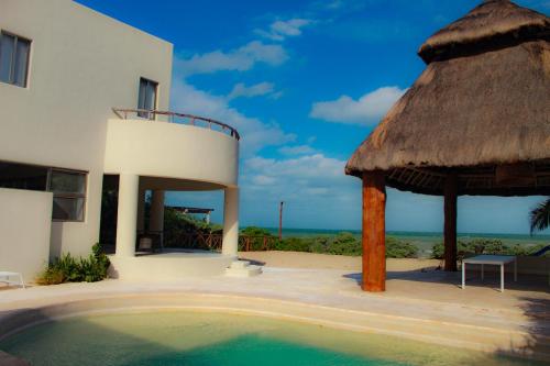 a house with a swimming pool and a thatch umbrella at Villa Karpatos in Progreso