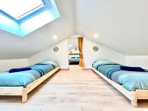 Duas camas num quarto com uma clarabóia em La havane, paisible gîte à 5 min du Futuroscope em Saint-Georges-lès-Baillargeaux