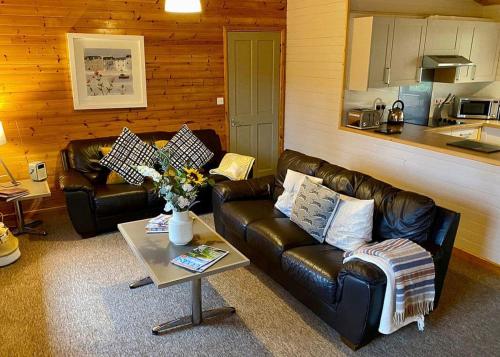 a living room with two leather couches and a coffee table at Ivyleaf Combe Lodges in Stratton