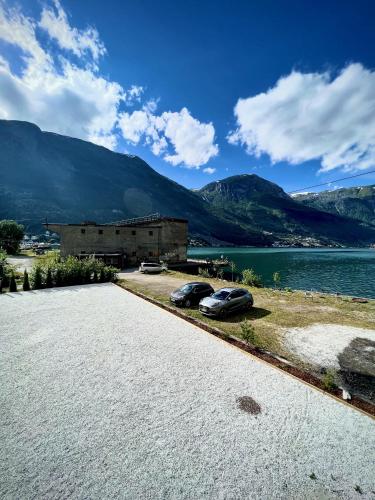 two cars parked on the side of a road next to a body of water at Trolltunga Studios in Odda