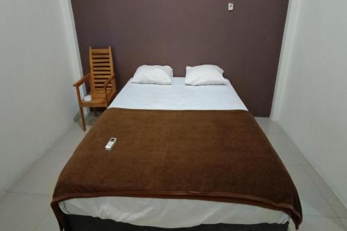- un lit avec une couverture brune au-dessus dans l'établissement OYO 92243 Fanilly Guest House Marabahan, à Banjarmasin