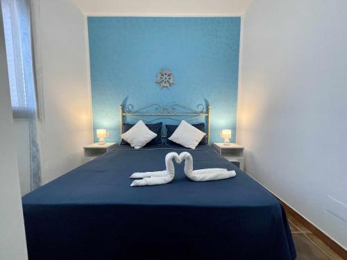 ランペドゥーザにあるDammusi cala croceの白鳥のタオル2枚(青いベッドの上に座る)