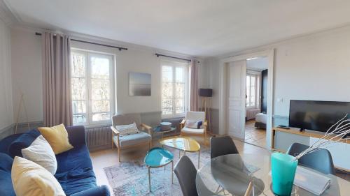 un salon avec un canapé bleu et une télévision dans l'établissement L'Appart du Quai avec Terrasse, à Strasbourg