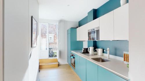a kitchen with blue and white cabinets and a sink at L'Appart du Quai avec Terrasse in Strasbourg
