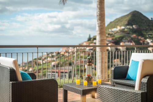 a patio with two chairs and a table with glasses on it at Palm Tree House in Câmara de Lobos