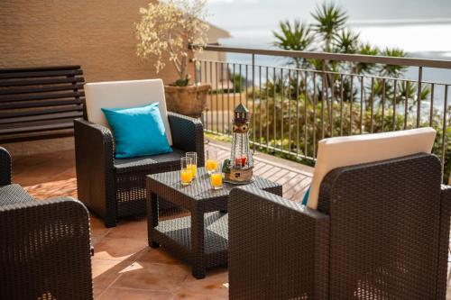 a patio with two chairs and a table with glasses on it at Palm Tree House in Câmara de Lobos
