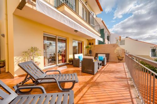 a patio with two chairs and a balcony at Palm Tree House by Amazing Madeira in Câmara de Lobos