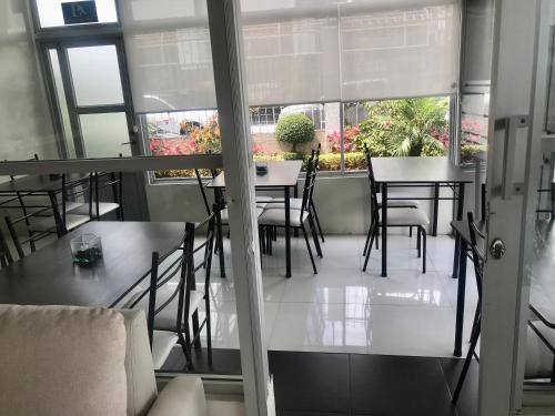 un comedor con mesas, sillas y ventanas en Floresta Inn Hotel, en Ambato