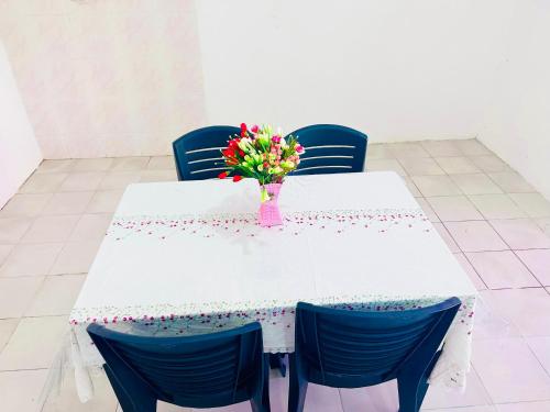 Bella Homestay Beaufort Sabah في بوفورت: طاولة بيضاء عليها إناء من الزهور