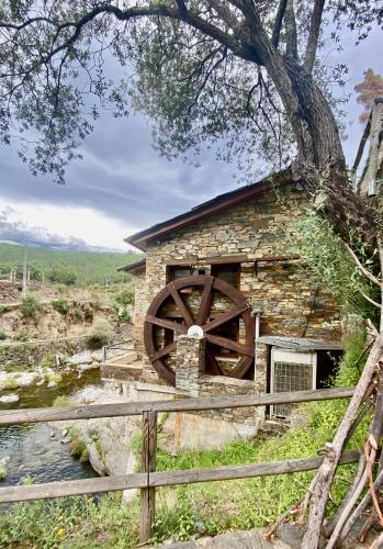 an old mill with a waterwheel in front of it at Love, made in xisto in Piódão