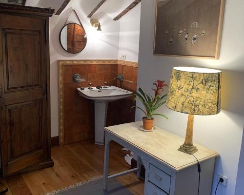 Carmona的住宿－El molino de La Infinita: Un coqueto molino con río propio，一间带水槽和台灯的桌子的浴室