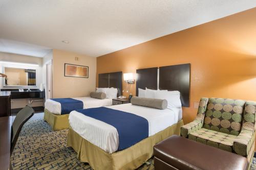 a hotel room with two beds and a chair at SureStay Hotel by Best Western Meridian in Meridian