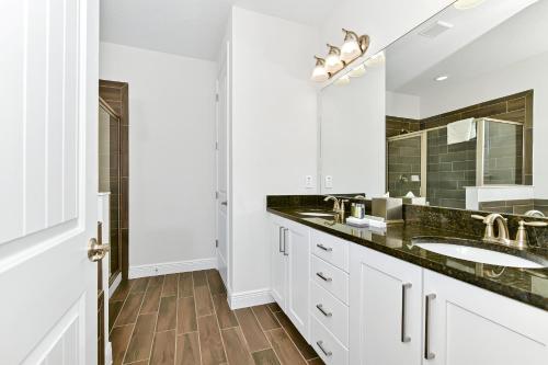 a white bathroom with two sinks and a mirror at ONIP - Luxurious Elite Home with Theater Room near Disney by Rentyl - 7604W in Orlando