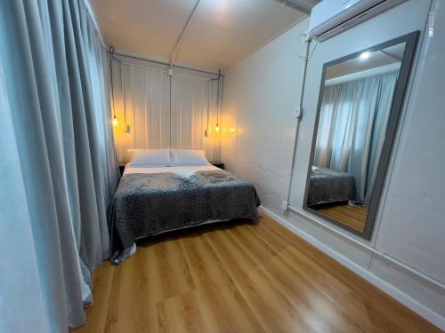 a small bedroom with a bed and a mirror at Pousada Container e Spa Mina Beer in Ametista do Sul