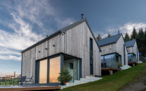 a barn style house with glass doors and windows at Domki z Górki na Pazurki in Falsztyn