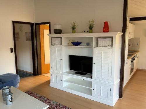 a white entertainment center with a television in a living room at Eckwarderhörne Objekt B 15 in Großwürden