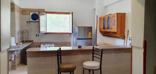 una cucina con un bancone con due sedie e un piano di lavoro di Nile View Panoramique and Garden West bank a Luxor