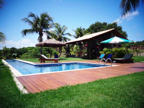 una piscina con sillas y sombrillas en un patio en Villa Angelim - Natureza e Conforto Barra do Cunhaú, en Barra do Cunhau