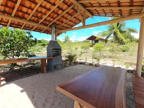 uma mesa de madeira sentada sob um pavilhão com um fogão em Villa Angelim - Natureza e Conforto Barra do Cunhaú em Barra do Cunhau