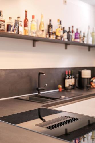 a kitchen counter with a sink and a shelf with bottles at Wohnen im Zentrum in Lindlar