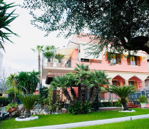 a pink building with palm trees in front of it at Ottaviano B&B in Ottaviano