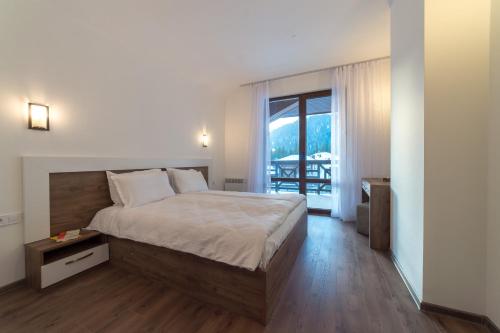 a bedroom with a large bed and a balcony at From Sunrise to Sunset at Oak Residence Smolyan Lakes in Pamporovo