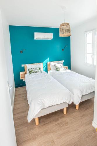 - 2 lits dans une chambre avec un mur bleu dans l'établissement LA CORVETTE Maison avec piscine/parking/wifi/plages 5kms, aux Mathes