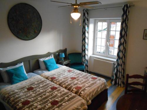 a bedroom with a bed with blue pillows and a window at Au Fief du Château in Orschwiller