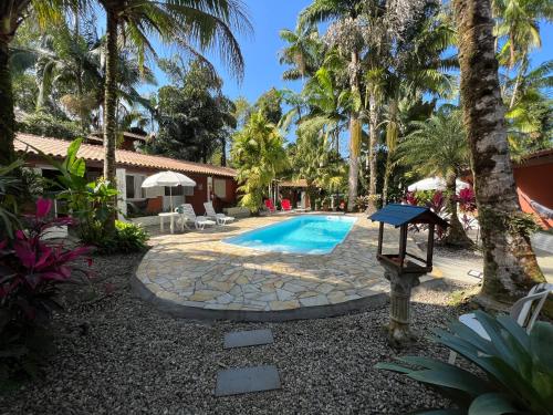 un patio trasero con piscina y palmeras en Pousada Nova Ascalom en Ubatuba
