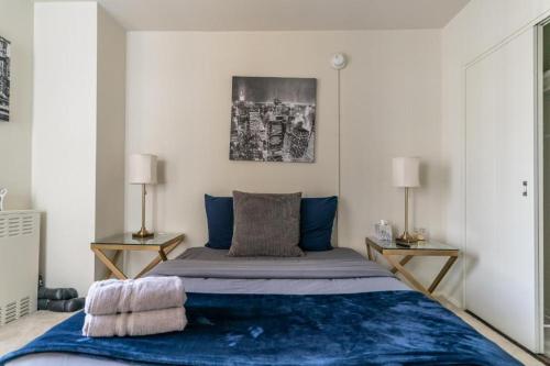 a bedroom with a bed with blue sheets and two lamps at Spacious Charming Condo with Great Views near the Grove in Los Angeles