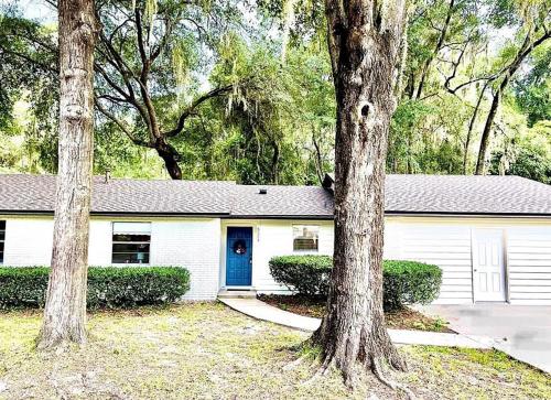 una casa bianca con una porta blu e due alberi di Spacious Gainesville Getaway with Pool and large private yard a West Hills