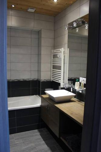 une salle de bain avec un lavabo, une baignoire et un miroir dans l'établissement Appartement vue sur le golf et le Lac Leman, à Publier