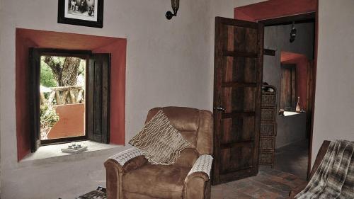 a living room with a leather chair and a window at Hacienda Sepulveda Hotel & Spa in Lagos de Moreno