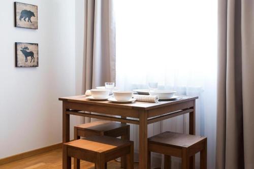 a wooden table with chairs and bowls on it with a window at Apartman DUSA in Kopaonik