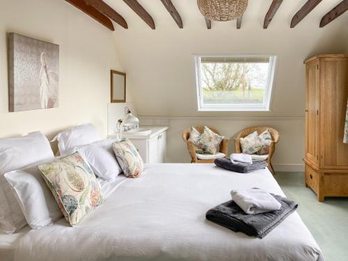 a bedroom with a large white bed with towels on it at Linnets in Fitzhead