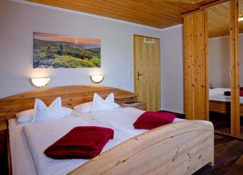 ein Schlafzimmer mit einem Bett mit zwei roten Kissen darauf in der Unterkunft Ferienlandhaus Brunner in Zachenberg