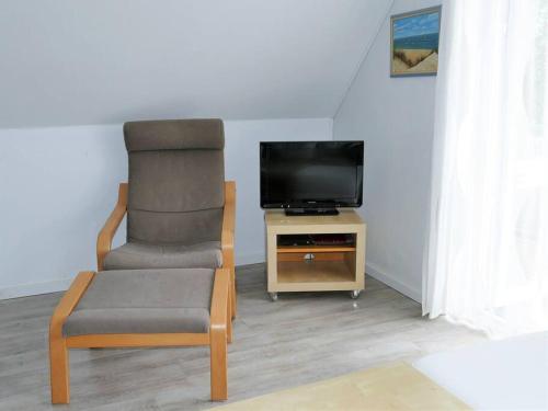 a living room with a chair and a television at Ferienwohnung: Utkiek in Langeoog