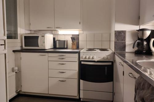 een keuken met een fornuis en een magnetron bij Kodikas yksiö keskustassa omalla autopaikalla in Joensuu