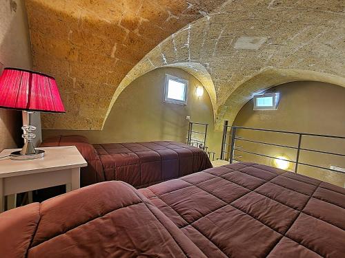 a bedroom with two beds and a table with a lamp at B&B Duca Orsini in Gravina in Puglia